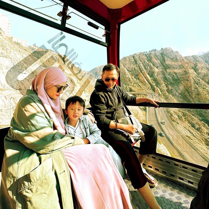 <p>Di sela waktu beribadah, pasangan ini juga menghabiskan momen bersama menikmati pemandangan Timur Tengah. Melalui unggahan di Instagram, Hanung membagikan momen ketika naik kereta gantung bersama sang istri dan putra bungsunya Kama.  (Foto: Instagram @zaskiadyamecca)</p>