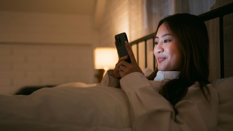 Ilustrasi mengirim ucapan selamat tidur Portrait of Asian teen girl lying in bed at night and using smartphone. Young woman lying in bed using smartphone for social media and watching series at late night. Insomnia, sleep disorder concept.