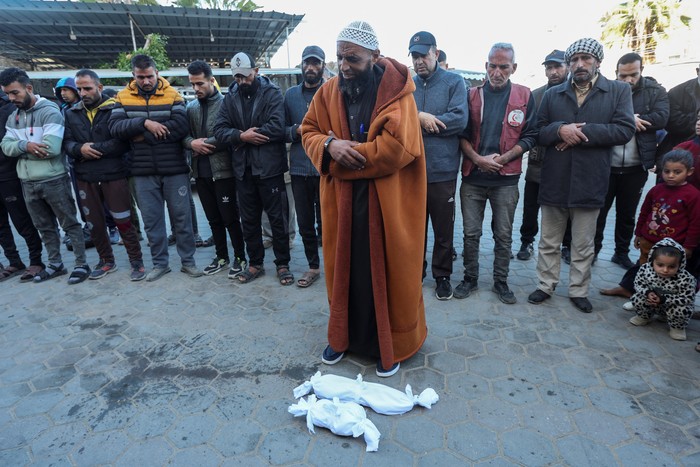 People pray next to the bodies of two Palestinian babies, including infant Jumaa Al-Batran, who died of hypothermia after living in a tent with his displaced family, at Al-Aqsa Martyrs Hospital in Deir Al-Balah in the central Gaza Strip, December 29, 2024. REUTERS/Ramadan Abed