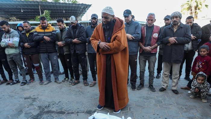 People pray next to the bodies of two Palestinian babies, including infant Jumaa Al-Batran, who died of hypothermia after living in a tent with his displaced family, at Al-Aqsa Martyrs Hospital in Deir Al-Balah in the central Gaza Strip, December 29, 2024. REUTERS/Ramadan Abed