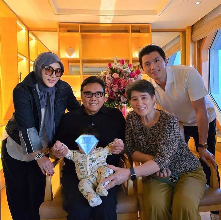 <p>Melalui <em>postingan</em> di Instagram, Syahrini membagikan momen saat Baby R menghabiskan waktu dengan kakek dan neneknya di Singapura. Dalam satu foto, tampak Baby R dipangku oleh ayah Reino Barack, yang duduk di sebelah istrinya. Di foto ini, ibunda Syahrini juga terlihat ikut berbagi momen spesial. (Foto: Instagram @princessyahrini)</p>