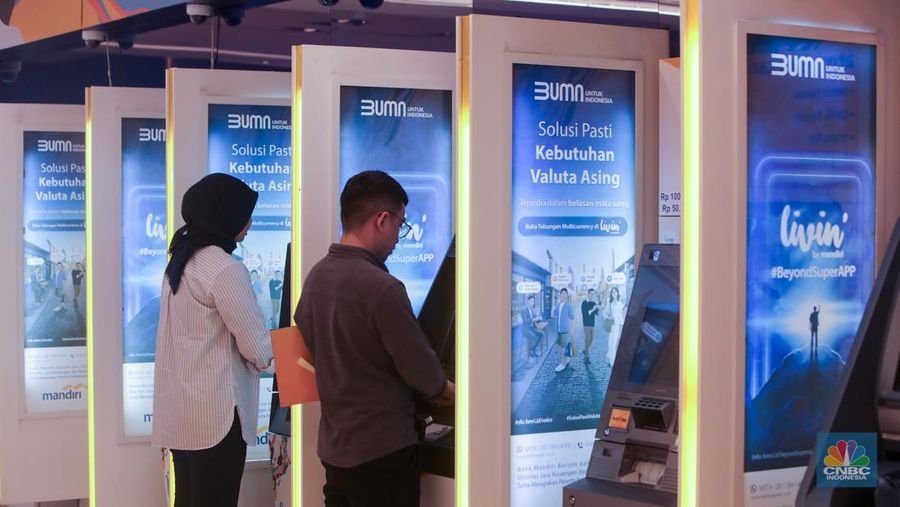 Sejumlah orang melakukan transaksi melalui mesin Anjungan Tunai Mandiri (ATM) di Bank Mandiri. (CNBC Indonesia/Faisal Rahman)