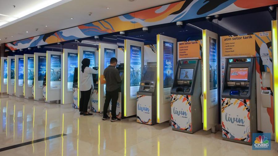 Sejumlah orang melakukan transaksi melalui mesin Anjungan Tunai Mandiri (ATM) di Bank Mandiri. (CNBC Indonesia/Faisal Rahman)