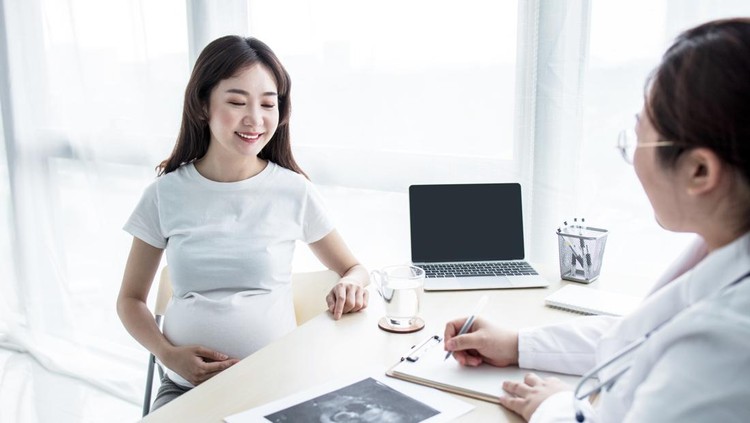 Pregnant woman with doctor looking at ultra sound photo in hospital