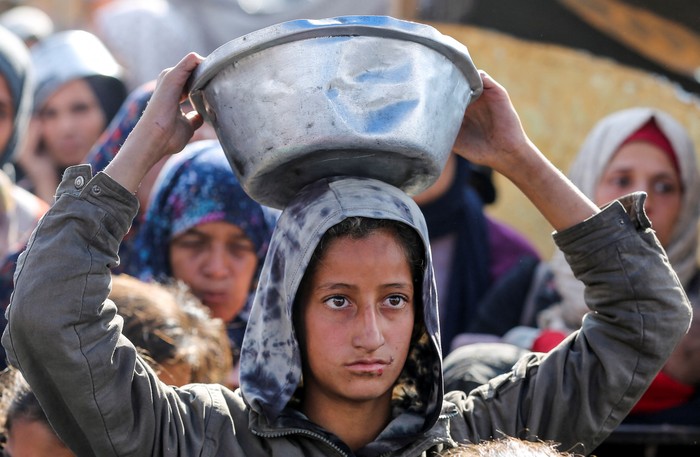 Palestinians gather to receive food cooked by a charity kitchen, before a ceasefire between Hamas and Israel takes effect, in Khan Younis, in the southern Gaza Strip, January 17, 2025. REUTERS/Hatem Khaled