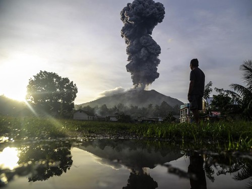 Seorang warga melihat erupsi dari kawah Gunung Ibu terlihat dari Desa Duono, Kabupaten Halmahera Barat beberapa waktu lalu.