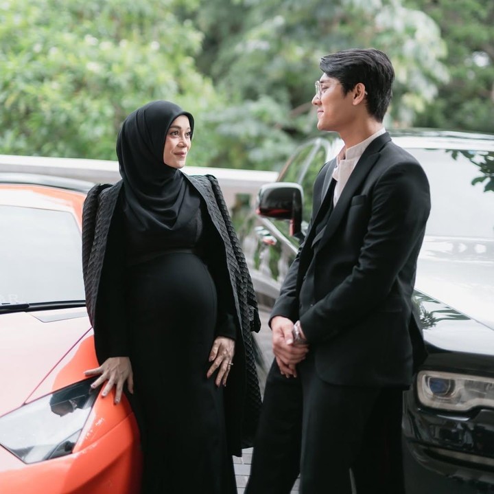 <p>Dalam foto yang diambil di <em>outdoor</em> ini, Lesti tampak memamerkan <em>baby bump</em> kehamilan keduanya yang dibalut dengan gaun hitam dan disempurnakan dengan jaket hitam. Lesti dan Rizky Billar berpose di depan dua mobil mewah. (Foto: Instagram @rizkybillar/ @lestikejora)</p>