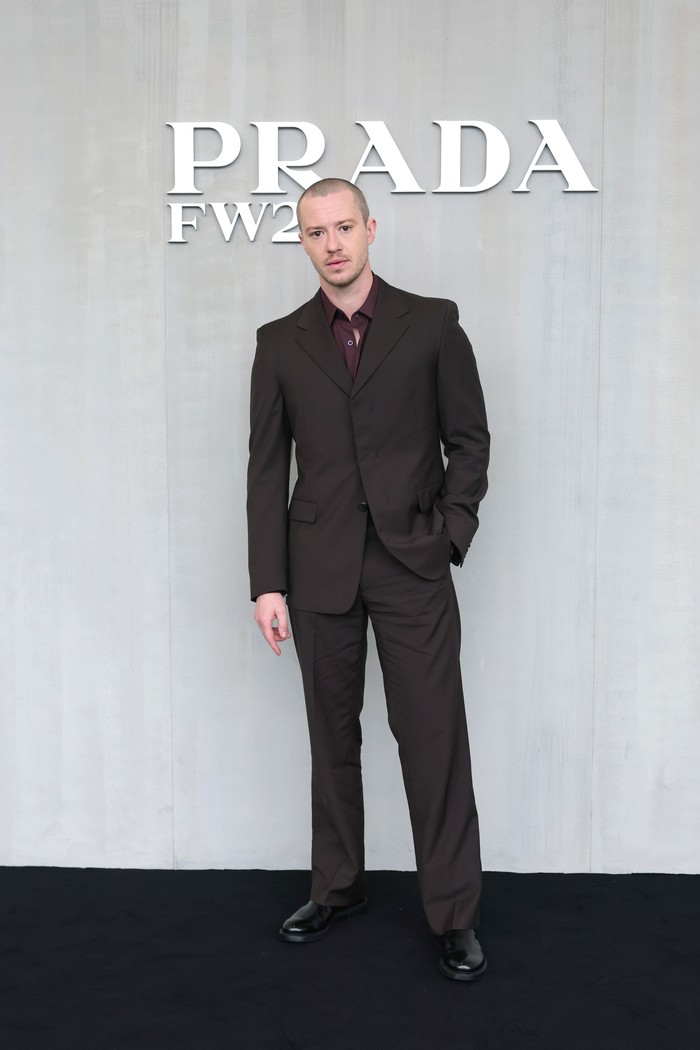 Bintang Stranger Things, Joseph Quinn, turut dijumpai di bangku front row, Beauties. Personanya berbeda saat ia mengenakan setelan jas coklat yang kian modis dipadu kemeja burgundy/ Foto: Dok. Prada