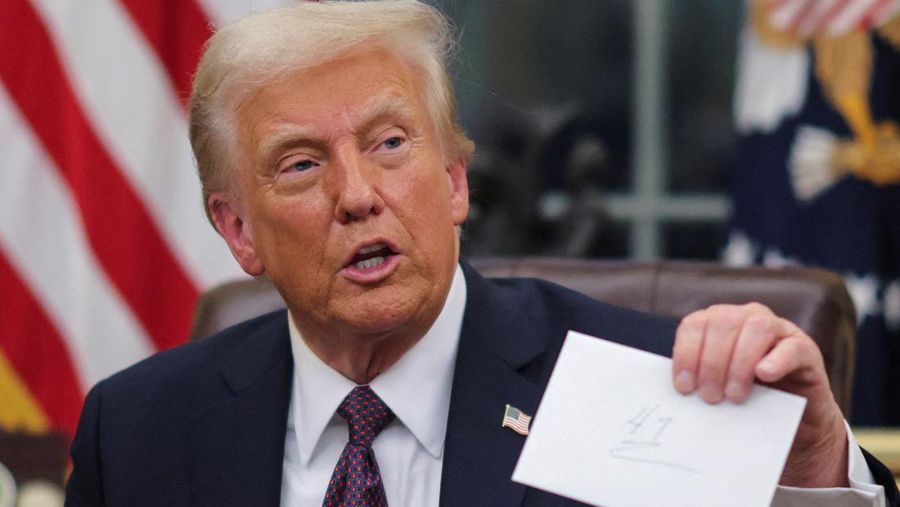 Presiden AS Donald Trump mengangkat surat dari mantan Presiden Joe Biden saat ia mengeluarkan perintah eksekutif dan pengampunan bagi para terdakwa 6 Januari di Ruang Oval di Gedung Putih pada hari pelantikan di Washington, AS, 20 Januari 2025. (REUTERS/Carlos Barria)