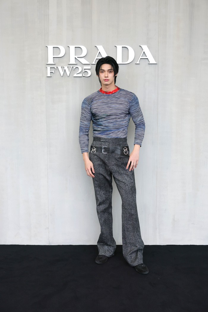 Sama seperti koleksi menswear Prada Fall/Winter 2025 yang menampilkan kontras dan kombinasi seduktif tak terprediksi, aktor asal Thailand, Win Metawin, turut beri kombinasi tak terduga lewat styling. Kaus lengan panjang bergaris horizontal disandingkan celana bergaris vertikal, sentuhan merah polkadot di kerah, sampai ikat pinggang leather aksen rings yang eksentrik/ Foto: Dok. Prada
