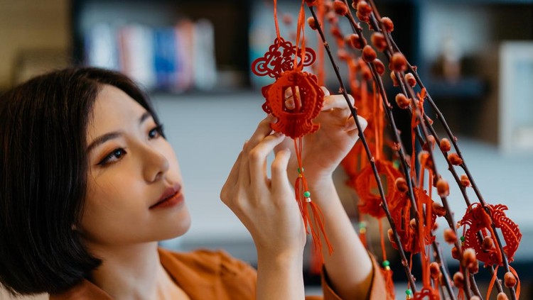 Image of an Asian Chinese woman hanging decoration on a plant and prepare for Chinese New Year