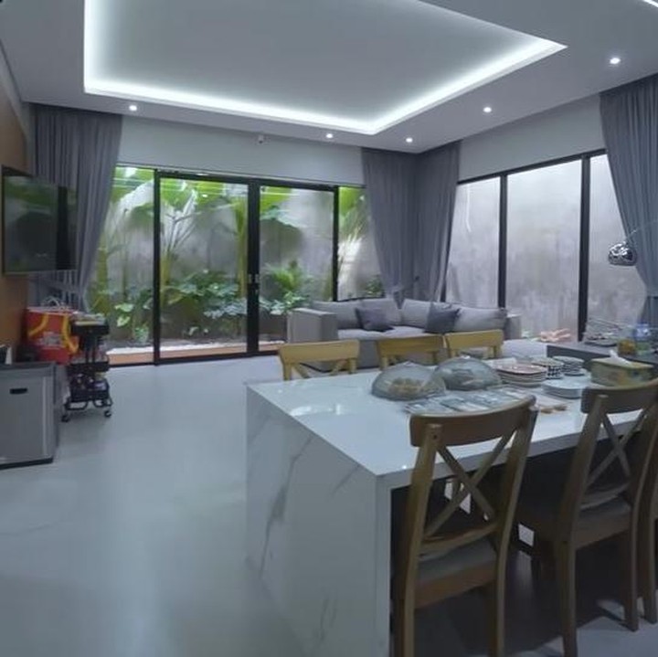 <p>Ruangan lain yang cukup menarik perhatian adalah ruang keluarga yang dijadikan satu dengan ruang makan dan dapur. Ruang keluarga yang didominasi warna abu-abu ini terletak di sudut ruangan dengan jendela dan pintu kaca transparan yang langsung menghadap ke balkon. Apip dan Shadira lalu membuat meja makan dari marmer putih di sudut lain ruangan di dekat dapur. (Foto: YouTube AH)</p>