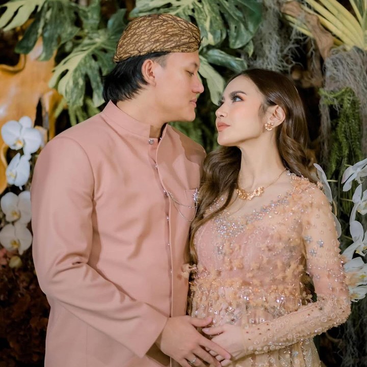 <p>Setelah mengumumkan kehamilannya ke publik di awal tahun 2025, penyanyi Mahalini menggelar acara tasyakuran tujuh bulan kehamilan. Acara ini dilangsungkan dengan mengusung adat Sunda, di mana Mahalini dan sang suami Rizky Febian kompak mengenakan pakaian adat bernuansa cokelat yang dipadu dengan kain batik sebagai bawahan. Pasangan ini menggunakan dekorasi bunga yang didominasi warna dokelat dan hijau. (Foto: Instagram @rizkyfbian/ @mahaliniraharja)</p>