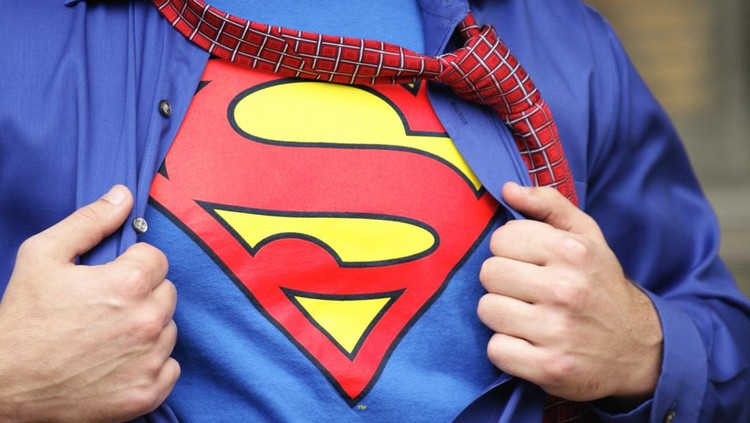 Penfield, New York, USA - October 30, 2009: Young man dressed in a Superman costume pulls off his outer shirt and tie.