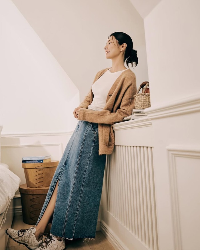Memadukan tampilan yang girly dan boyish dengan kaus putih yang dibalut cardigan cokelat dan rok jins panjang serta menyempurnakannya dengan sneakers./ Foto: Instagram.com/havv_y