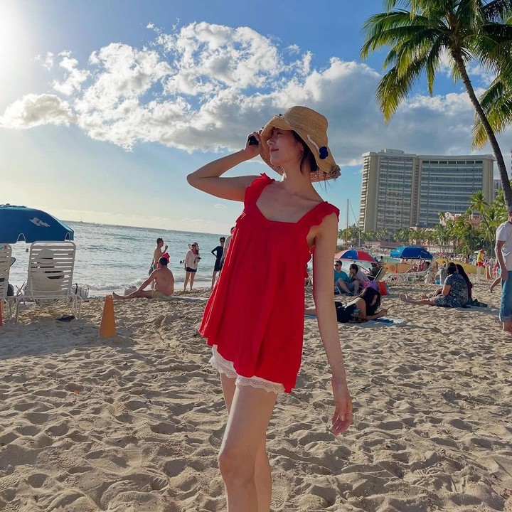 <p>Saat bermain di pantai, ia juga tampil feminin mengenakan <em>mini dress</em> berwarna merah yang dipadukan dengan celana pendek berwarna putih. Ia pun melengkapi penampilannya itu dengan topi pantai. (Foto: Instagram@somin_jj)</p>