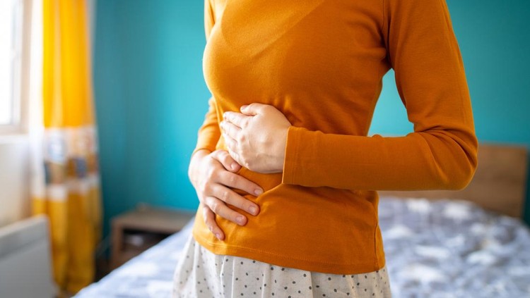 A young woman is having pain in her stomach and holding it with both hands