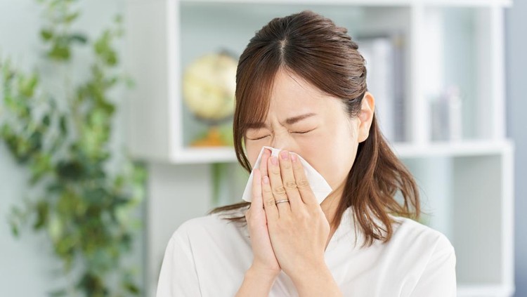Ilustrasi flu atau influenza A woman blowing her nose due to rhinitis