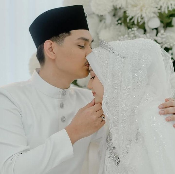 <p>Di acara pernikahannya, Yasmine kembali mengenakan gaun putih. Kali ini, ia mengenakan hijab putih yang dihiasi mahkota berwarna perak. Dalam satu foto yang diunggah, Yasmine tampak tersenyum manis saat sang suami mengecup keningnya. (Foto: Instagram @yxsmine.ow)</p>