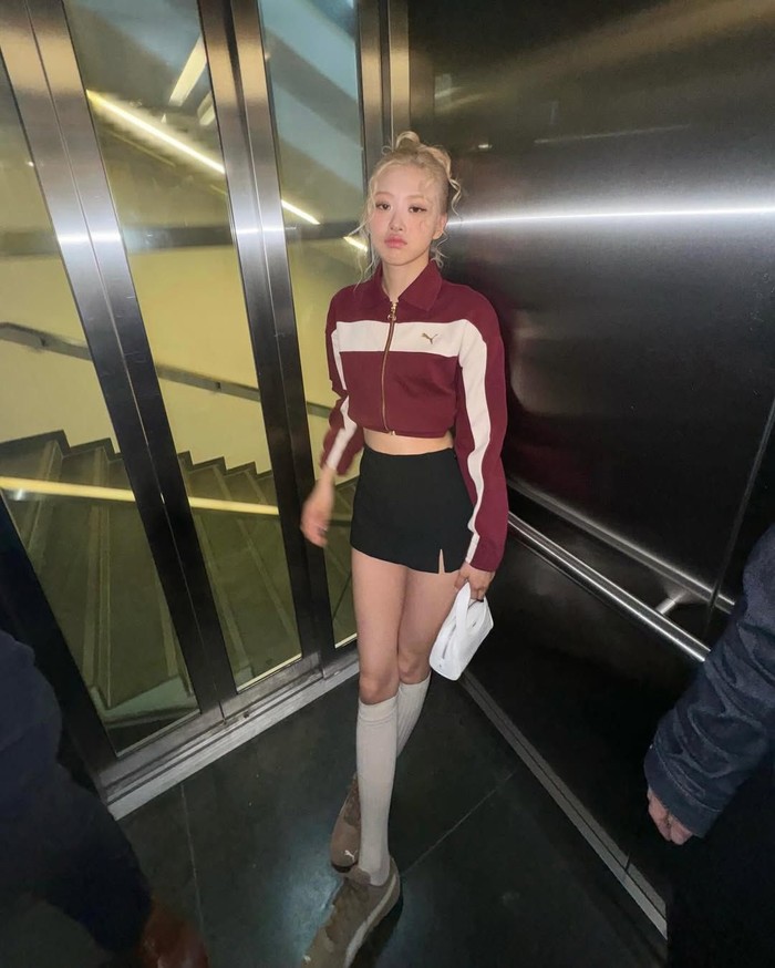 Kaus kaki putih panjang selutut juga Ros&eacute; padukan dengan sneakers santai yang sempurna dengan outfit rok mini hitam dan cropped jacket merah yang chic./ Foto: Instagram/roses_are_rosie