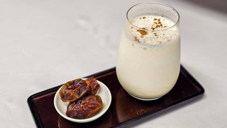 Dates and date smoothie with cinnamon powder on the top and serve with rectanguler tray.