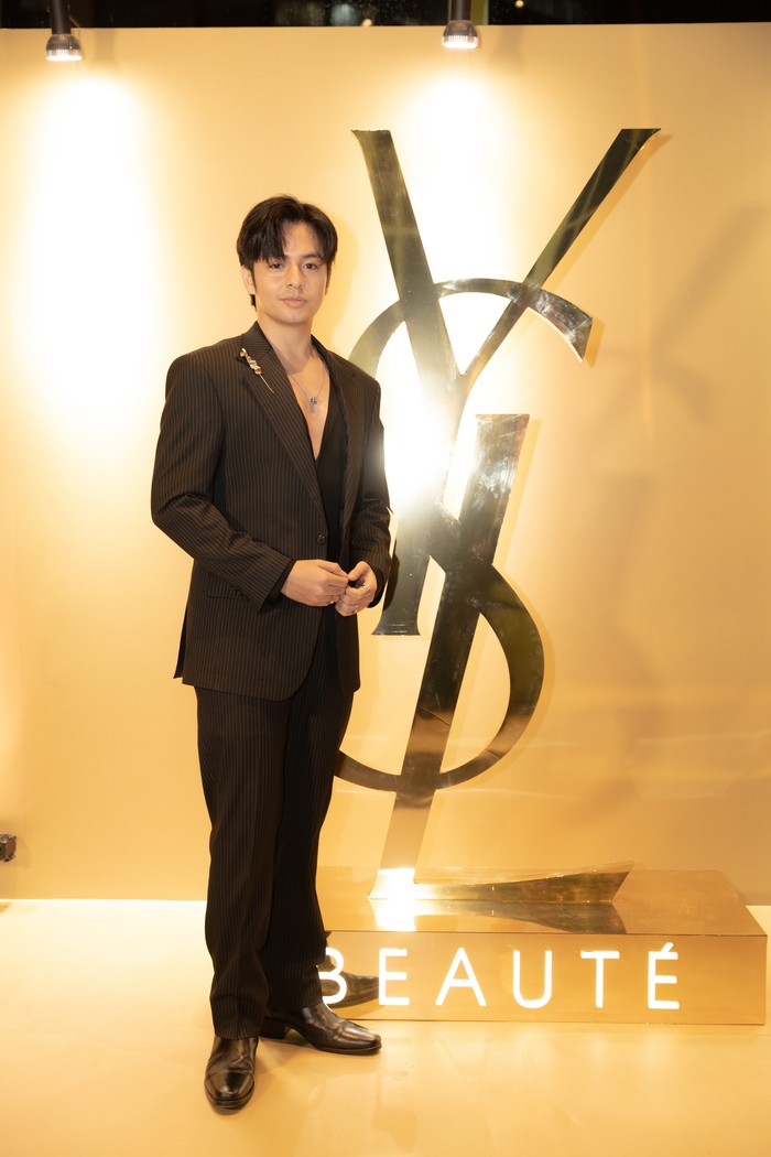 Angga Yunanda fashionable mengenakan pinstripe suit coklat dengan sematan bros emas sculptural yang serasi. Padu padan dengan kemeja hitam polos dan kalung pendant perak simpel menarik atensi ke setelan jas./ Foto: Dok. YSL Beauty/VINCENTIUS