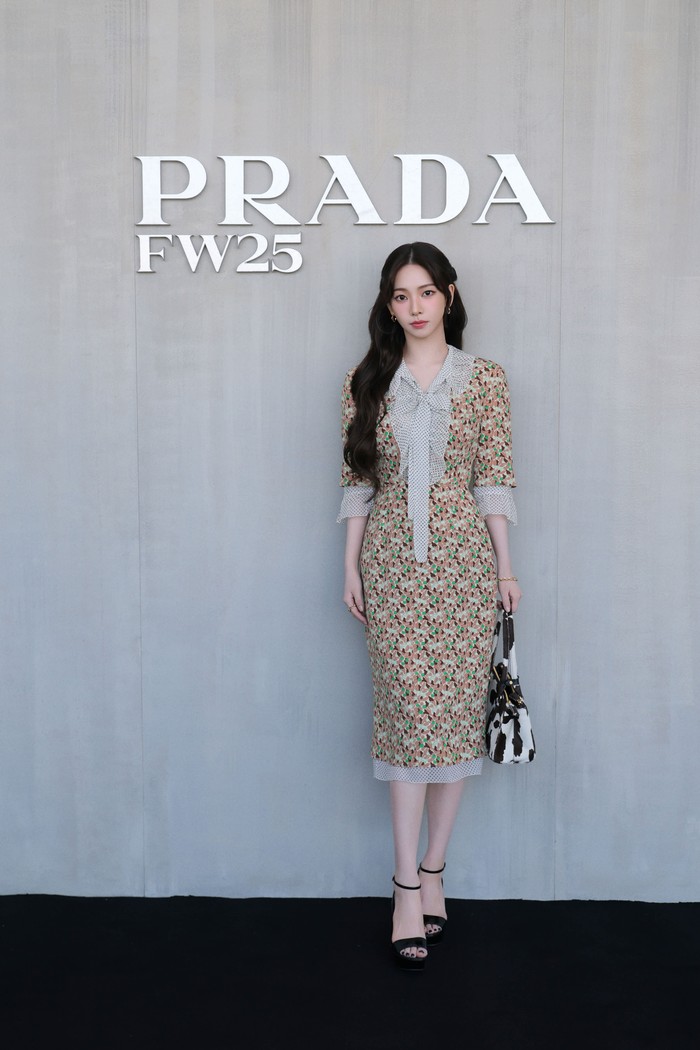 Karina aespa memesona dalam tampilan chic, Beauties. Simple, ia mengenakan midi dress dalam corak multi warna yang disandingkan motif polkador pada kerah pita, hemline, dan lengan. Untuk memusatkan gaya pada dress tersebut serta tas tangan motif sapi, minimalist heels dan perhiasan simple dipakainya/ Foto: Courtesy of Prada