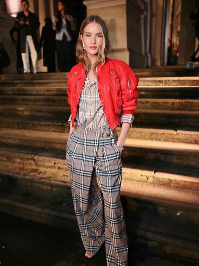 Rosie Huntington-Whiteley buktikan kalau Burberry plaid yang ikonis bisa jadi fashion statement stylish dengan padu padan tepat. Sang model mengenakan kemeja dan celana panjang siluet longgar dikombinasi dengan biker jacket merah yang mengaksentuasi gayanya/ Foto: Courtesy of Burberry/Dave Benett/Dave Benett