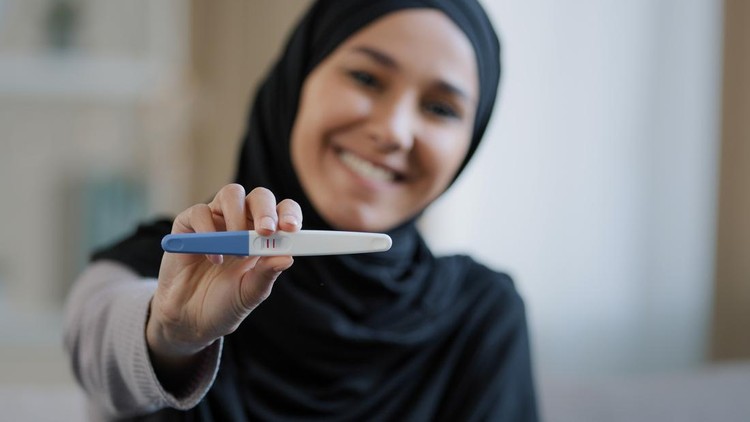 test pack Joyful islamic young woman in hijab smiling happily holding pregnancy test excited pregnant lady surprised and happy celebrating good news future mother shows positive result muslim female expect baby. High quality photo