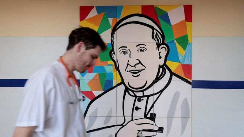 Orang-orang berdoa dalam dekat patung mendiang Paus Yohanes Paulus II pada luar Rumah Sakit Gemelli tempat Paus Fransiskus dirawat, dalam Roma, Italia, 5 Maret 2025. (REUTERS/Remo Casilli)