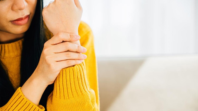 Illustrating hand pain, Woman holds her achy wrist indicating Carpal Tunnel Syndrome or discomfort. Emphasizing inflammation symptoms and discomfort in the hand's anatomy. Health care concept