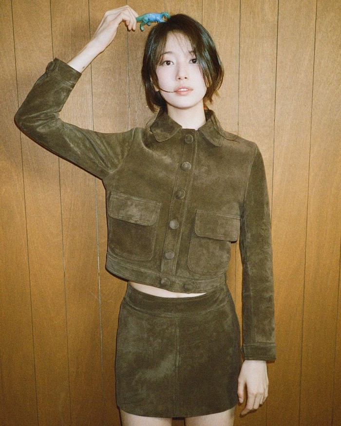 Suzy mengenakan jaket suede coklat, yang sedang tren saat ini. Jaket pendek dengan saku dipadukan dengan rok mini one set menciptakan tampilan simpel namun tetap bergaya vintage./ Foto: Instagram/skuukzky