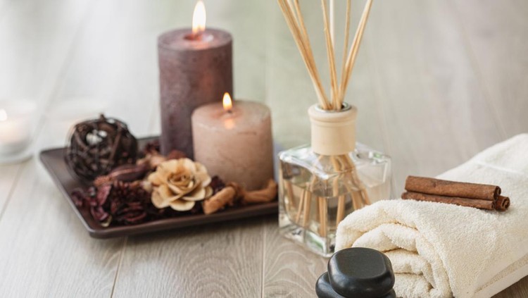 Copyspace of wooden floor in a spa center where different tools are ready for a relaxing session of massage and mindfulness. Volcanic stones, towel, candles and aroma diffuser are visible.