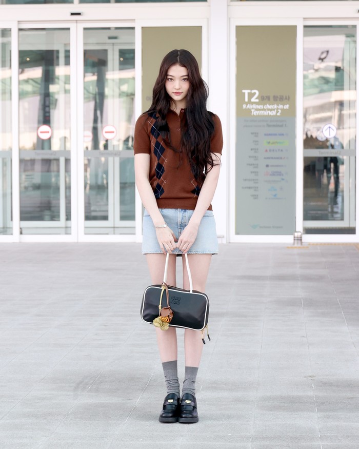 Simple, yet mysterious. Airport fashion ala Ella Gross berhasil memancarkan pesona tersebut. Sweater coklat motif argyle dan platform shoes menuai impresi preppy, tapi lebih kasual ketika dipadu denim miki skirt dan shoulder bag Miu Miu Beau bergantung charms/ Foto: Dok. Miu Miu