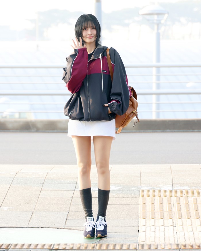 Siapa yang nggak terpesona dengan gaya sporty chic Momo Twice ini? Track jacket Miu Miu dipadu mini skirt putih yang girly, tapi tetap nyaman. Momo turut mengenakan sneakers yang dipasangkan dengan kaus kaki hitam serta backpack tersampir di pundak/ Foto: Dok. Miu Miu