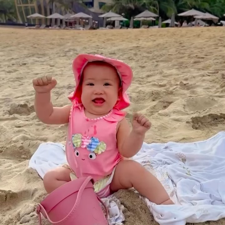 <p>Pada video yang sama, terlihat pula Kyarra terduduk dan mengambil pasir dari dalam ember. Ia kemudian melemparkan pasir tersebut sambil tertawa girang. (Foto: Instagram: @jscmila)</p>