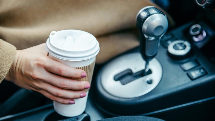 woman hand taking cup with coffee in car. close up. crop. morning energy. lifestyle