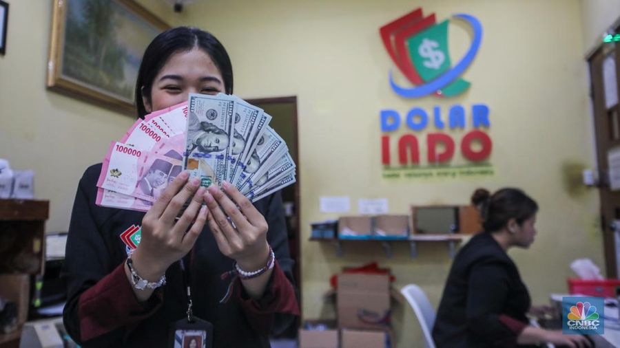 Petugas menjunjukkan uang pecahan dolar AS dan rupiah di Dolarindo Money Changer, Jakarta, Selasa (8/4/2025). (CNBC Indonesia/Faisal Rahman)