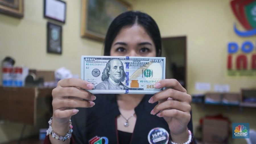 Petugas menjunjukkan uang pecahan dolar AS dan rupiah di Dolarindo Money Changer, Jakarta, Selasa (8/4/2025). (CNBC Indonesia/Faisal Rahman)