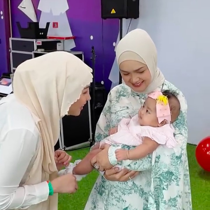 <p>Aghnia terlihat menggemaskan dengan dress merah muda dan bando di kepala. Ia pun sangat anteng ketika digendong oleh sang nenek. (Foto: TikTok: @tyaarifinnw)</p>