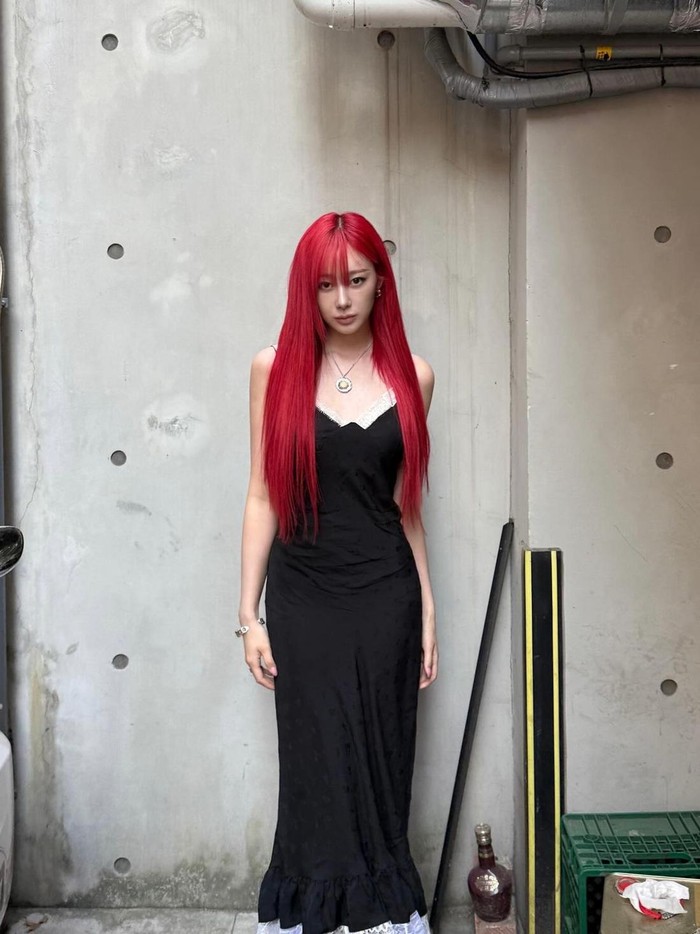 Tampilan dress slip hitam Gisele memberikan kontras dramatis pada rambut merahnya. Kombinasi lipatan dan detail renda menambah kesan gotik pada outfit-nya./ Foto: Instagram/aerichandesu