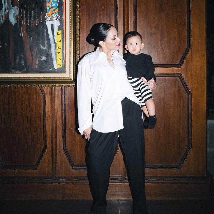 <p>Sambil menggendong sang putra, Angel tampil cantik dengan kemeja putih dan celana hitam. Sementara itu, Caspar sangat menggemaskan dengan kaos hitam dan celana garis-garis. (Foto: Instagram: @angelpieters)</p>