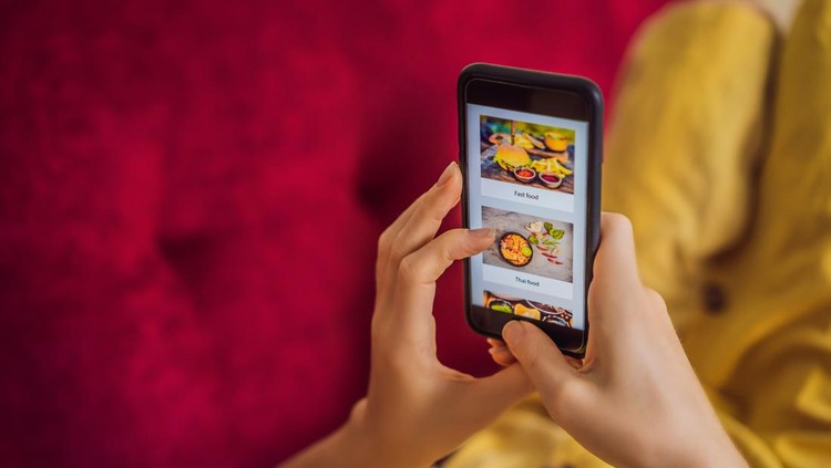 Ilustrasi diskon Young woman orders food for lunch online using a smartphone.