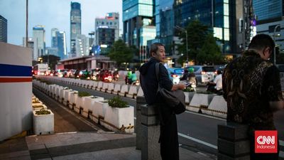 Pekerja tampak melintasi pelican crossing saat jam pulang kerja di kawasan Jalan Jendral Sudirman, Jakarta, Senin (5/5/2025).