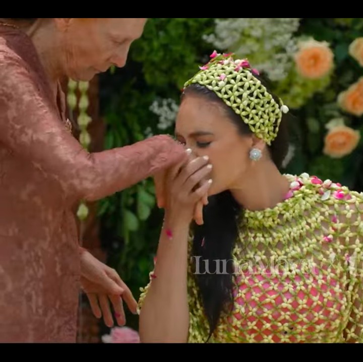 <p>Sang Bunda menjadi orang pertama yang menyirami Luna Maya. Setelahnya, Luna pun mengecup punggung tangan sang Bunda penuh kasih. (Foto: YouTube TS Media)</p>