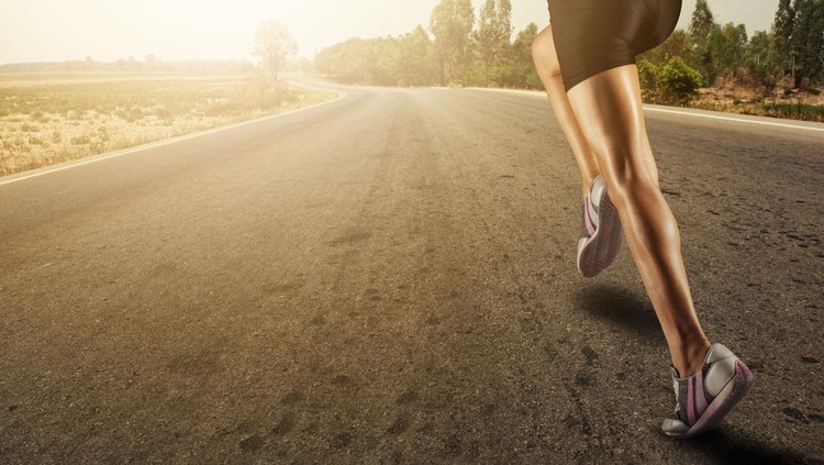 Sports background&period; Runner feet running on road closeup on shoe&period;flare light