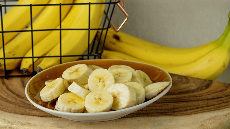 Fresh bananas and bananas cut into pieces in a bowl on the table - stock photo