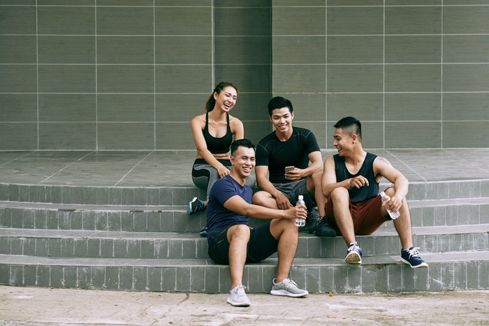 Laughing friends sitting outdoors, laughing and chatting after training