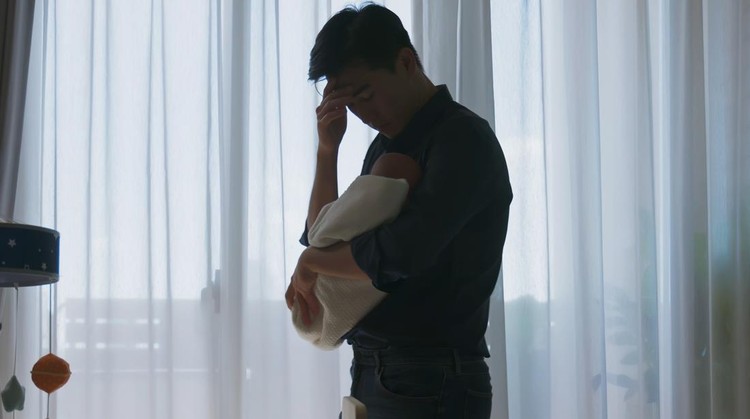 silhouette asian man holding his baby feel depressed about being new dad while standing by windows