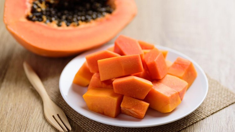 Ilustrasi buah pepaya Sliced ripe papaya fruit on plate and fork ready to eating, Tropical fruit